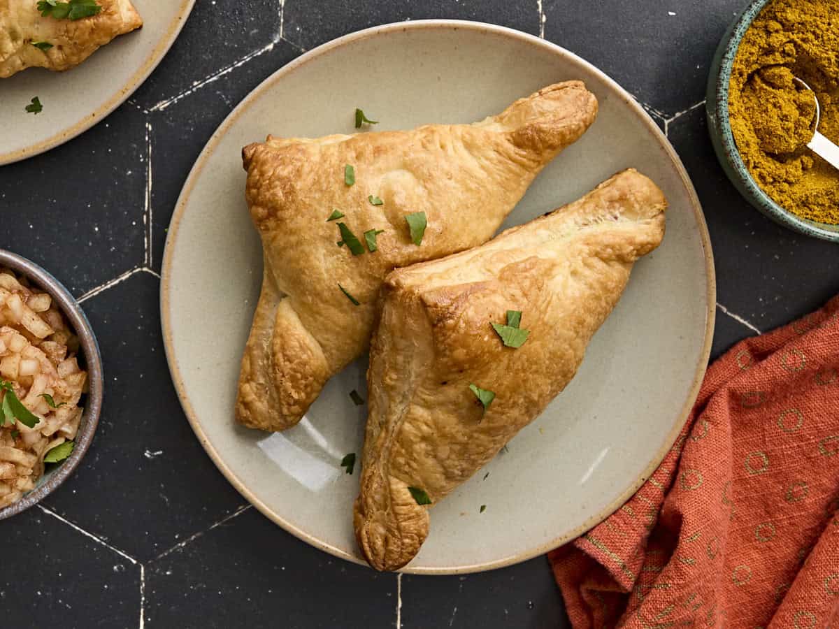 Overhead view of two puff pastry samosas on a plate.