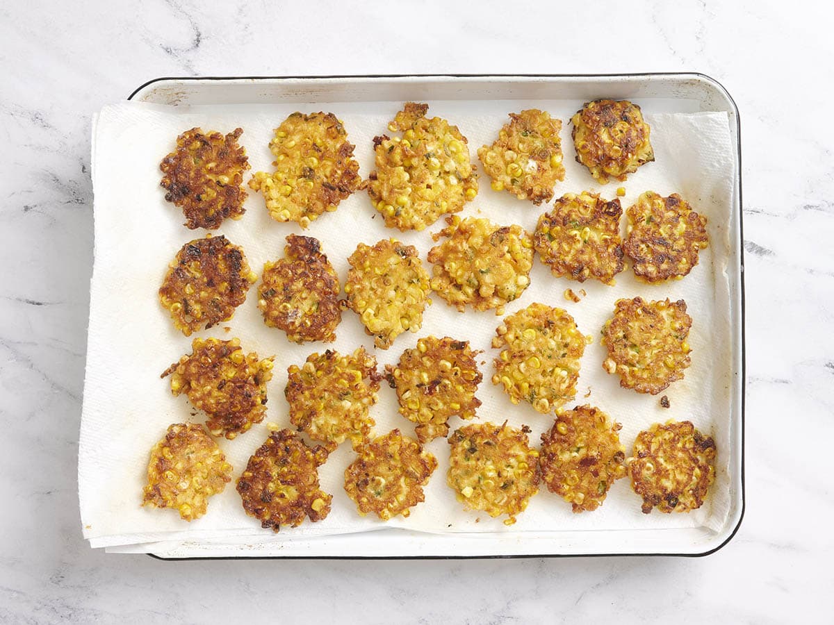 Homemade sweet corn fritters on a paper towel lined baking sheet.