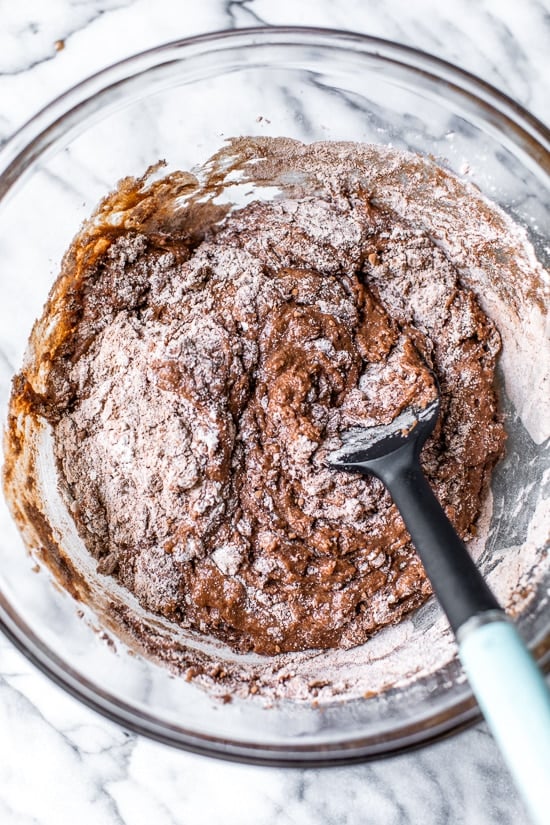 This Chocolate Zucchini Bread is so rich and delicious, no one will guess that it's secretly healthy! Add walnuts for crunch in every bite. Overhead view of dry ingredients added to bowl of wet ingredients for chocolate zucchini bread