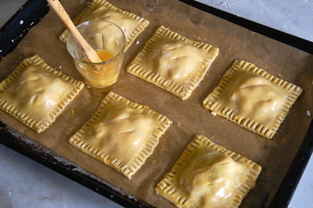 hand pies on a baking sheet after brushing with egg wash