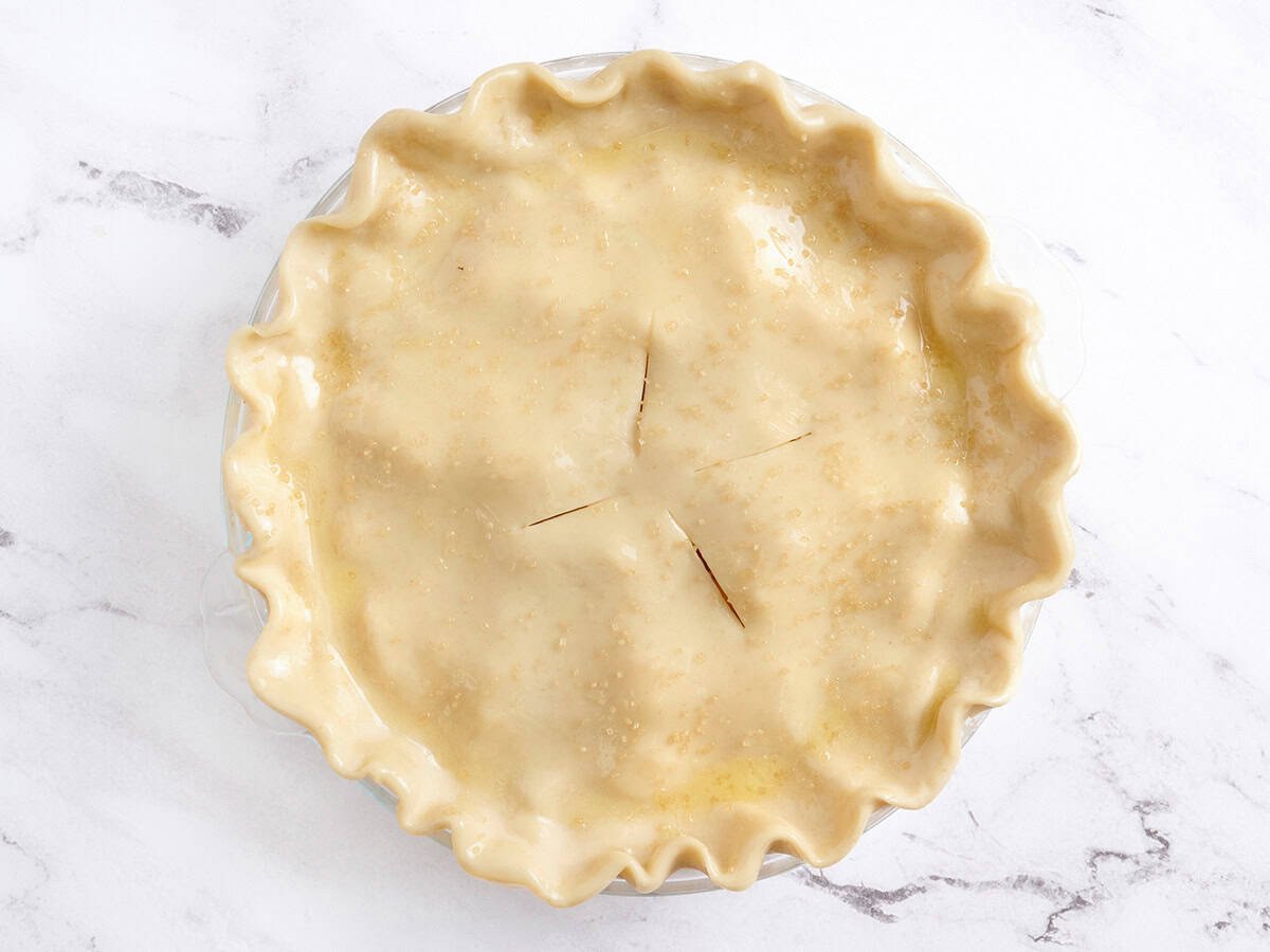 An unbaked peach pie in a pie dish.