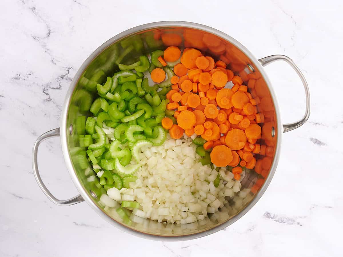 Diced onion, carrots, and celery in a soup pot.