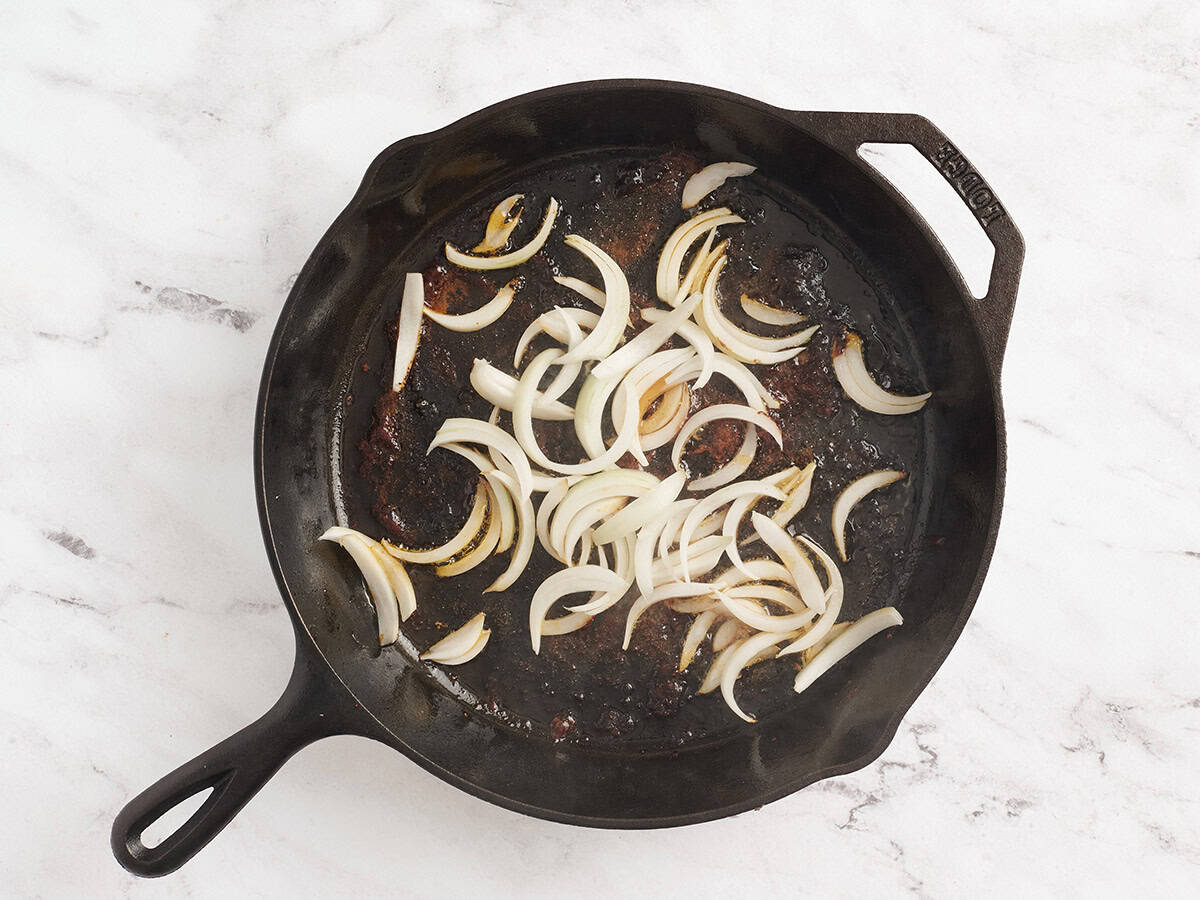 Sliced onion softening in a skillet.