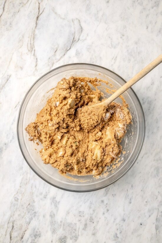 Overhead view of apple scone dough in glass bowl with wooden spoon
