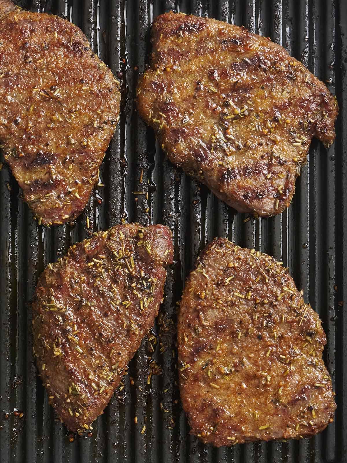 Overhead view of grilled tender steaks on a grill.