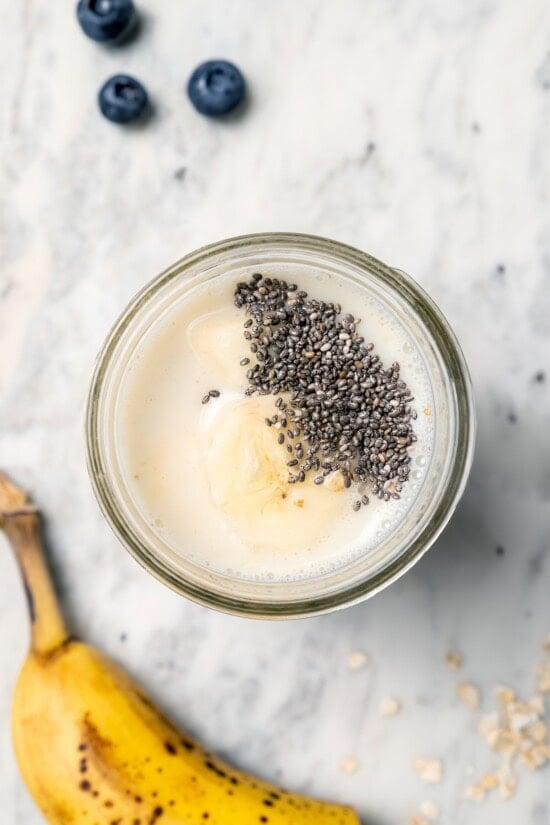 Overhead view of chia seeds added to jar of overnight oats