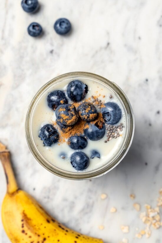Overhead view of overnight oats in jar with blueberries and cinnamon on top