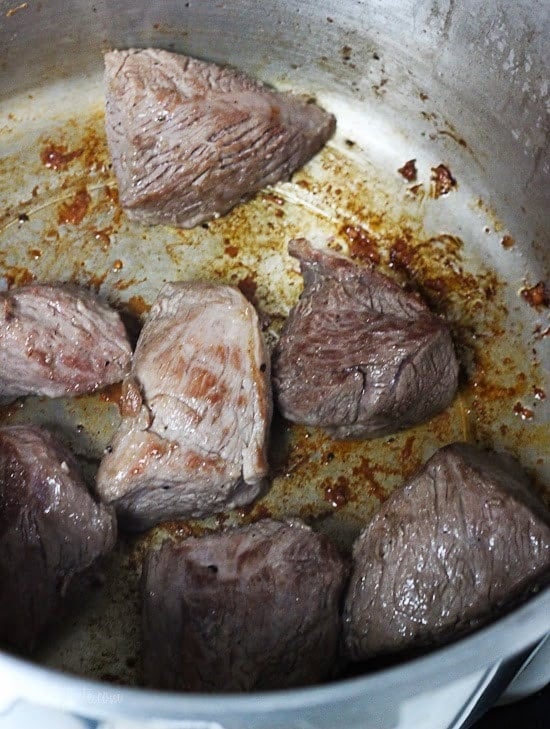 This Instant Pot Pozole Rojo recipe is easier and faster than the classic version! With pork, hominy and spices, it's hearty and flavorful. Pork browned in Instant Pot for pozole rojo.