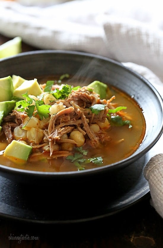 This Instant Pot Pozole Rojo recipe is easier and faster than the classic version! With pork, hominy and spices, it's hearty and flavorful. Bowl of pozole rojo with avocado and cilantro for garnish.