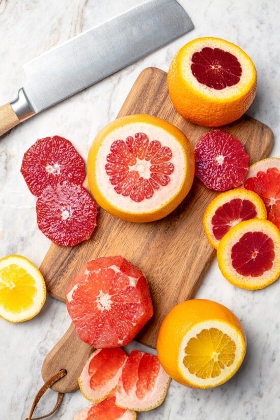 Sliced citrus fruit on cutting board set next to knife.