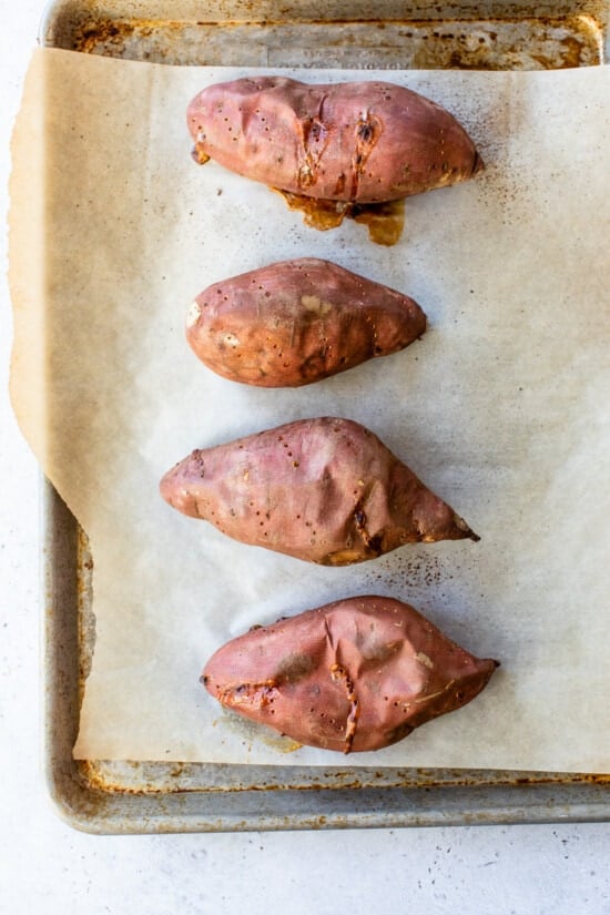 Baked sweet potatoes on parchment lined sheet pan.
