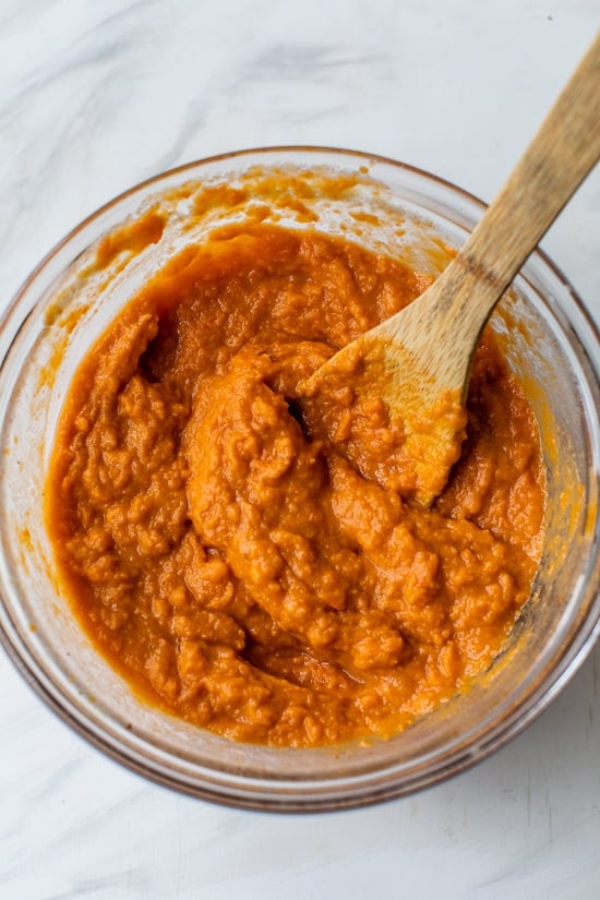Stirring ingredients for sweet potato casserole in bowl.