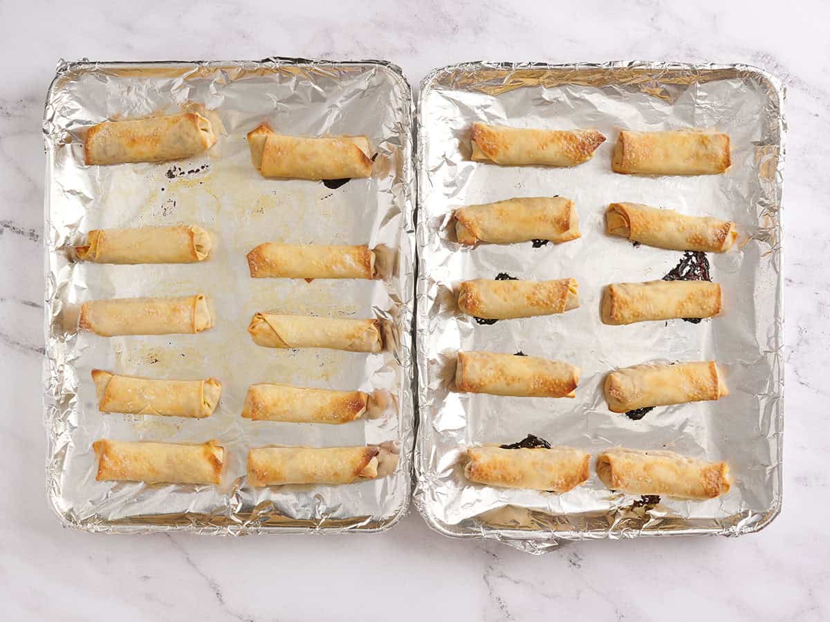 Baked vegetable egg rolls on a foil lined baking sheet.