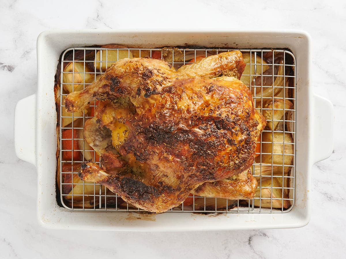 Roasted chicken in a baking dish set over vegetables.