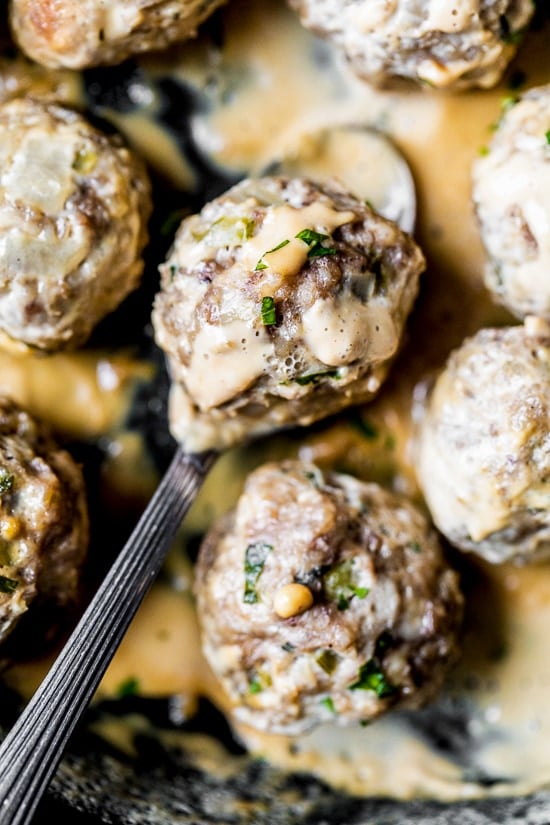 Swedish meatball in spoon with creamy gravy.