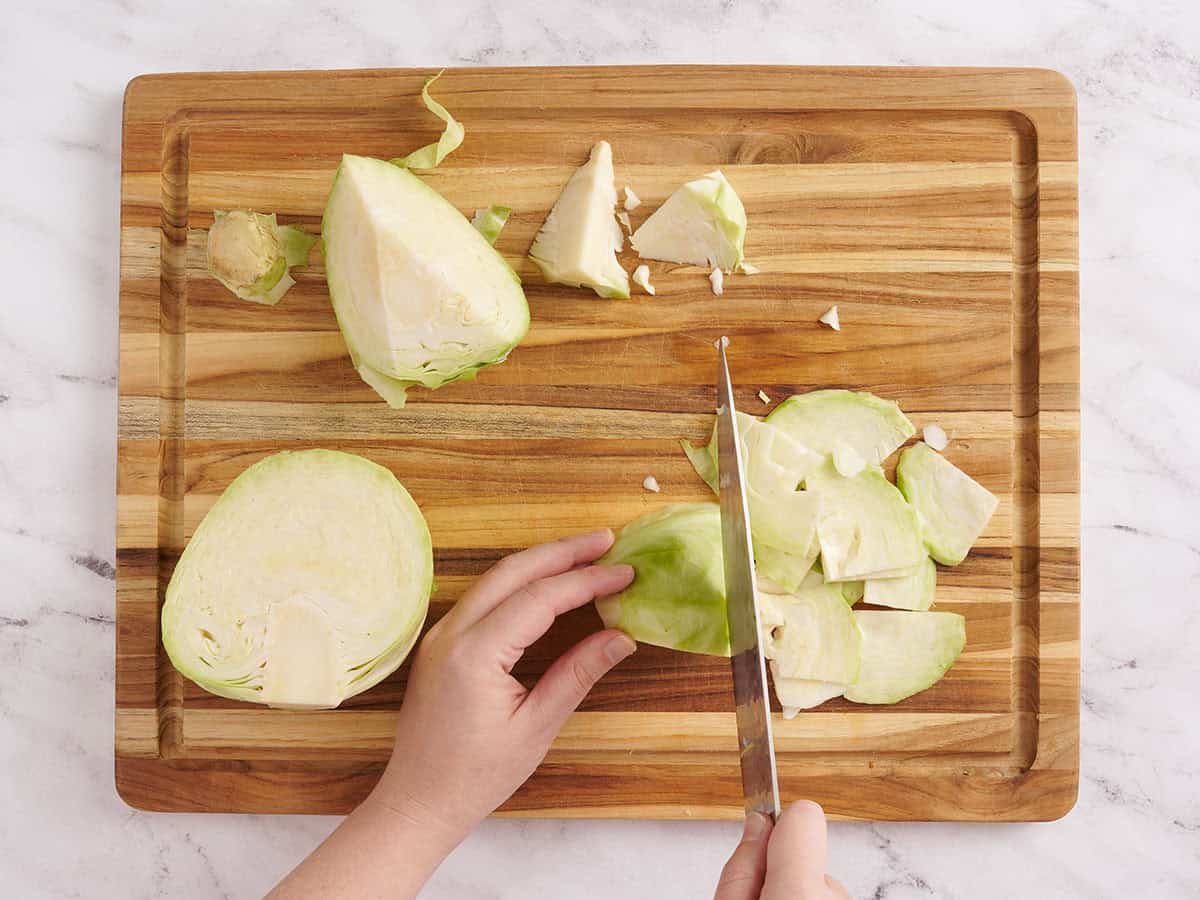 A hand using a knife to slice cabbage.