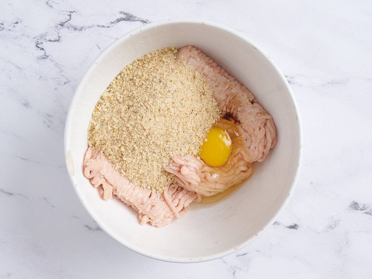Ground chicken, egg, and breadcrumbs in a bowl.