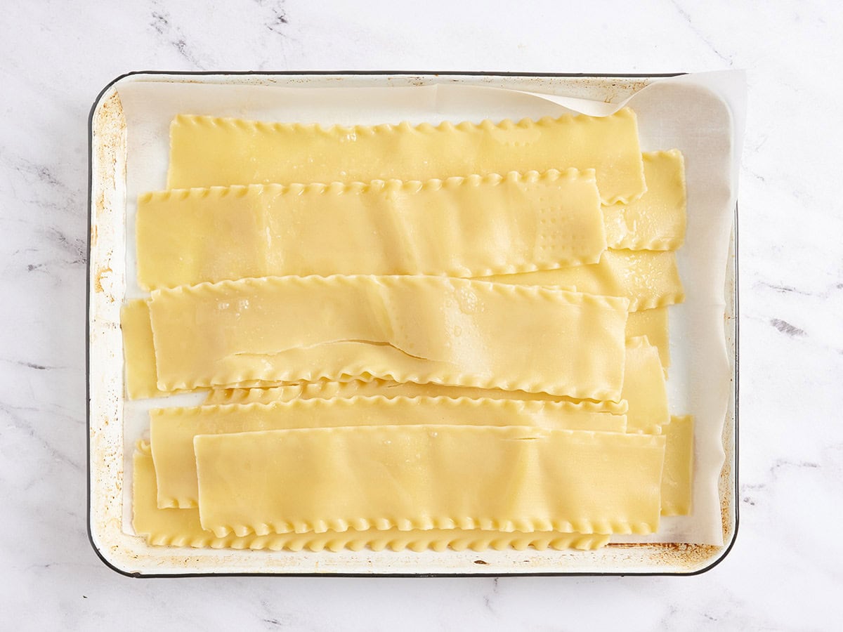 Cooked lasagna noodles on a baking sheet.