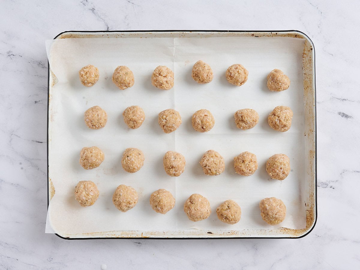 Formed chicken meatballs on a baking tray.