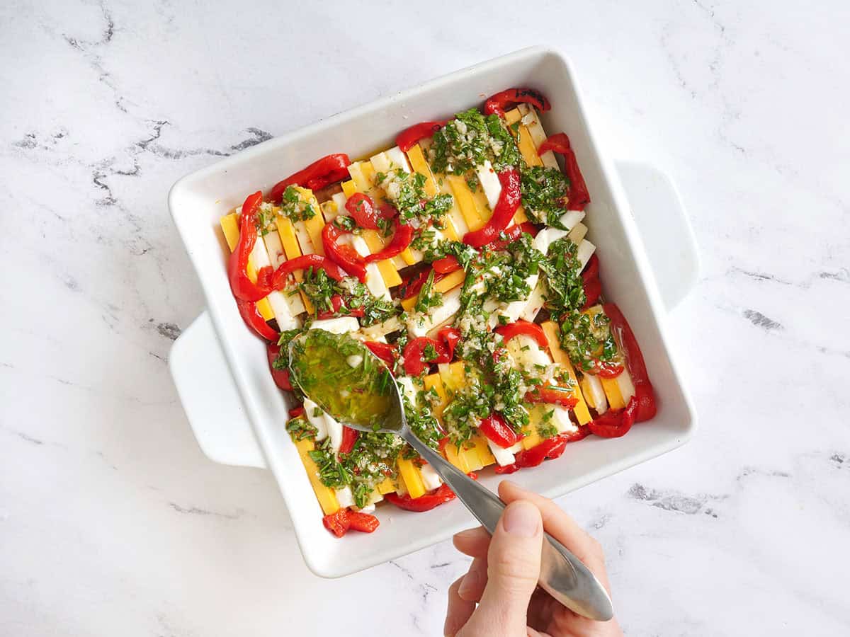 Sliced cheese arranged in a baking dish and topped with a marinade.