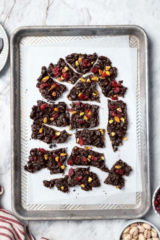 Dark chocolate bark broken into pieces on parchment paper.
