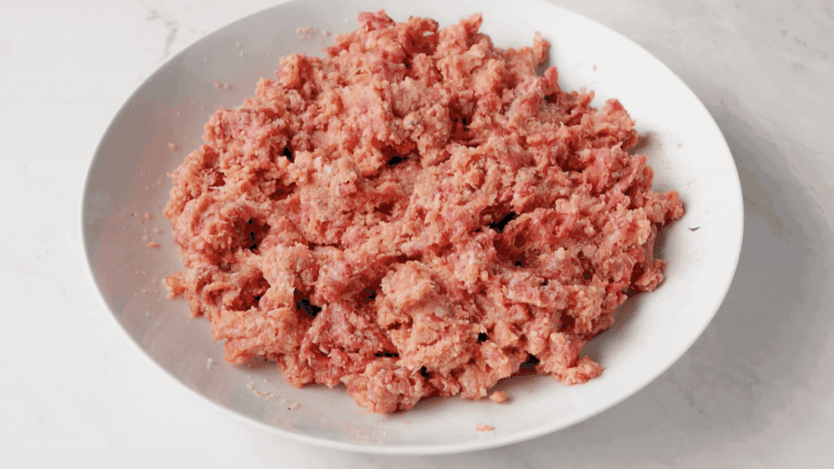 A formed meatball being held.