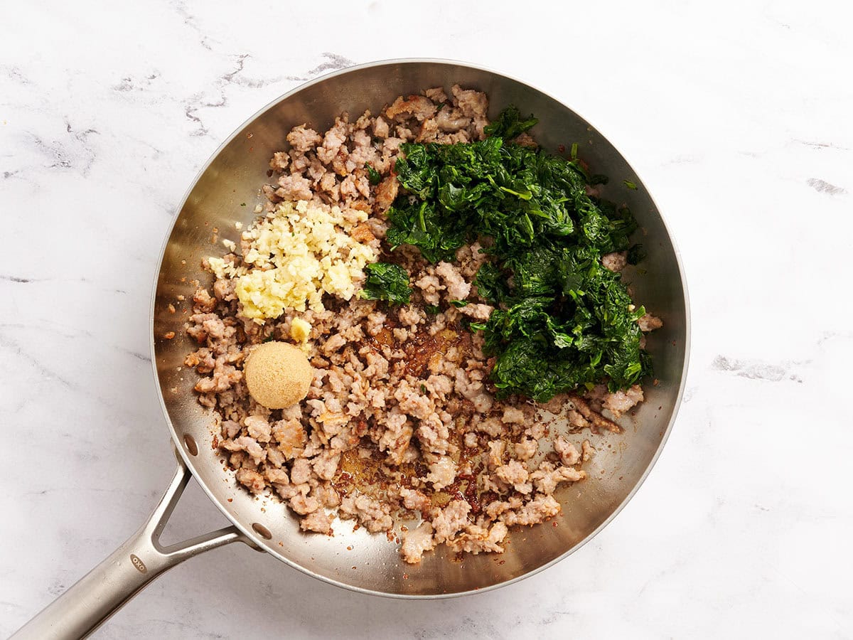Browned ground pork, spinach, sugar and aromatics in a skillet.