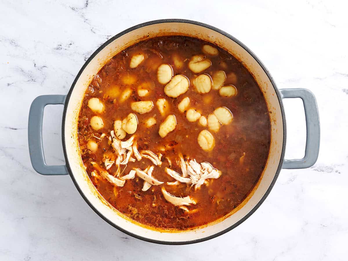 Adding gnocchi and returning the shredded chicken to the soup pot. 
