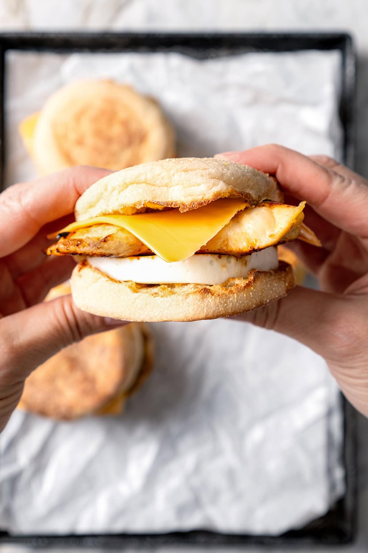 Two hands holding egg white grill breakfast sandwich.