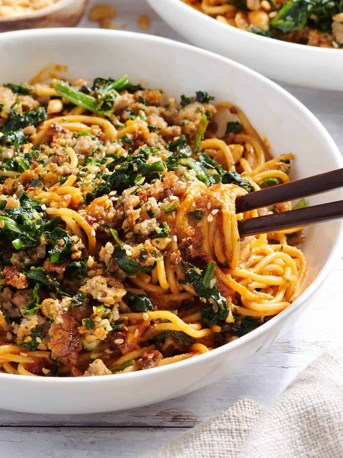 Side view of a bowl of dan dan noodles with chopsticks.Overhead view of a bowl of dan dan noodles with chopsticks.
